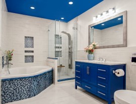 A careful balance can be achieved if you are careful with your tile choices. A dark blue and white bathroom with accent tiles on the bathtub and a dark blue ceiling and sink.