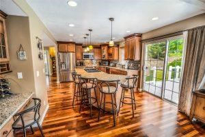 Wood can bring warmth to your kitchen A kitchen island with barstools and wood kitchen flooring